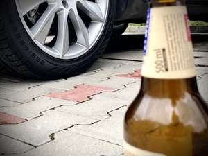 Butelka po piwie na tle koła samochodowego Butelka po piwie na tle koła samochodowego