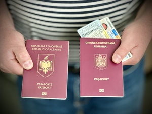Paszport albański, rumuński oraz rumuńskie prawo jazdy i dowód osobisty trzymane w rękach 