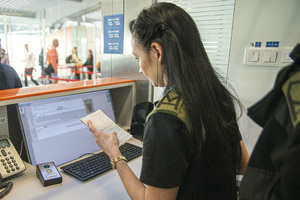 Funkcjonariuszka SG  sprawdza paszport. Funkcjonariuszka SG  sprawdza paszport.