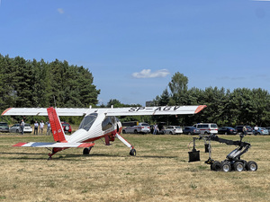 Na trawie stoją od lewej samolot Wilga i robot pirotechniczny. Na trawie stoją od lewej samolot Wilga i robot pirotechniczny.