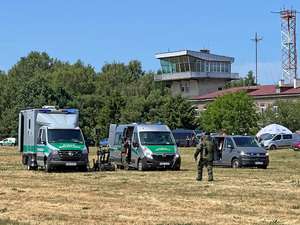 Samochody Straży Granicznej stoją na terenie lotniska. W tle widać lotniskowe budynki. Samochody Straży Granicznej stoją na terenie lotniska. W tle widać lotniskowe budynki.