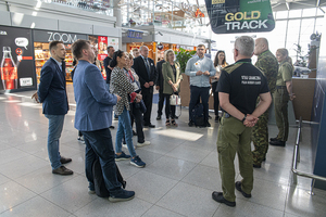Uczestnicy wizyty stoją w terminalu lotniska, patrzą w stronę funkcjonariuszy. Uczestnicy wizyty stoją w terminalu lotniska, patrzą w stronę funkcjonariuszy.