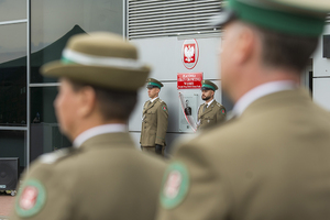 Na pierwszym planie funkcjonariusze stojący tyłem w tle asysta przy tablicy pamiątkowej Patrona PSG w Łodzi Na pierwszym planie funkcjonariusze stojący tyłem w tle asysta przy tablicy pamiątkowej Patrona PSG w Łodzi