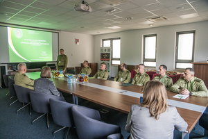 Sala konferencyjna. Uczestnicy spotkania siedzą przy stole, na ekranie wyświetlana jest prezentacja. Sala konferencyjna. Uczestnicy spotkania siedzą przy stole, na ekranie wyświetlana jest prezentacja.