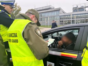 Funkcjonariusze stoją przy samochodzie. Kontrolują dokumenty kierowcy. Funkcjonariusze stoją przy samochodzie. Kontrolują dokumenty kierowcy.