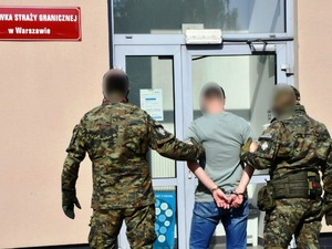 Funkcjonariusze wprowadzają mężczyznę do Placówki Straży Granicznej. Funkcjonariusze wprowadzają mężczyznę do Placówki Straży Granicznej.