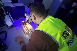 Technik kryminalistyki bada dokument pod mikroskopem. Technik kryminalistyki bada dokument pod mikroskopem.