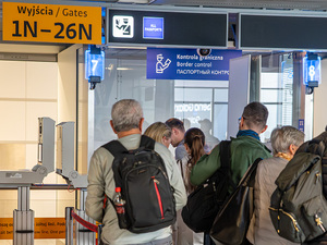 Podróżni stoją przed kabinami kontroli granicznej. Podróżni stoją przed kabinami kontroli granicznej.