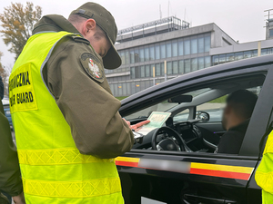 Funkcjonariusz stoi przy samochodzie i sprawdza dokument. Funkcjonariusz stoi przy samochodzie i sprawdza dokument.