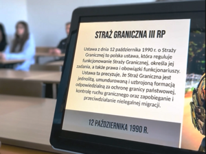 Monitor w tle siedzą uczniowie. Monitor w tle siedzą uczniowie.