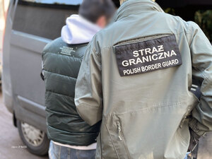 Funkcjonariusz wprowadza cudzoziemca do samochodu służbowego. Funkcjonariusz wprowadza cudzoziemca do samochodu służbowego.