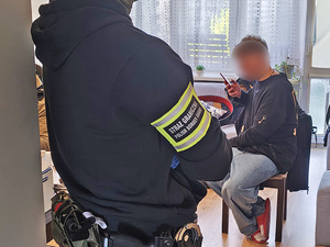 Funkcjonariusz patrzy na cudzoziemca siedzącego przy stole. Funkcjonariusz patrzy na cudzoziemca siedzącego przy stole.