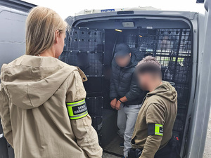 Cudzoziemiec wysiada z pojazdu w asyście funkcjonariuszy. Cudzoziemiec wysiada z pojazdu w asyście funkcjonariuszy.