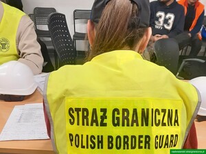 Funkcjonariuszka siedzi przy stole w żółtej kamizelce. Funkcjonariuszka siedzi przy stole w żółtej kamizelce.